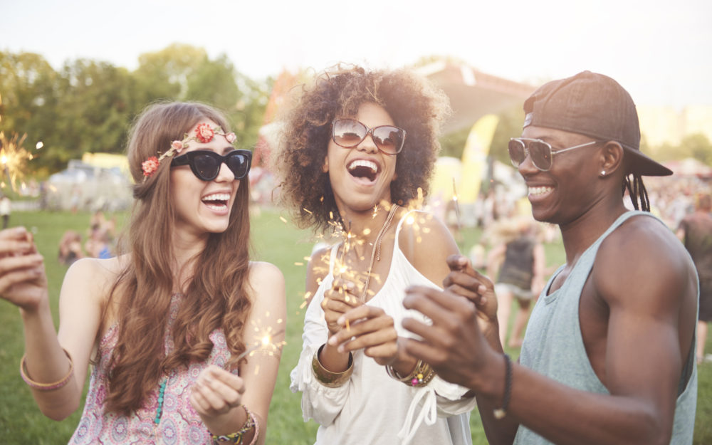 Drei Freunde feiern mit Wunderkerzen auf einem Open Air Fest