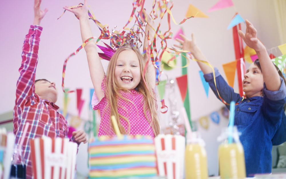 Kinder feiern mit Deko-Papierschlangen und Wimpeln Kindergeburtstag