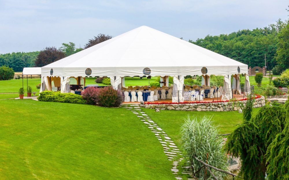 Ein großes Zelt auf einer grünen Wiese mit einer Gala-Bestuhlung als Festzelt.