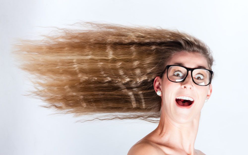 Frau mit großen Augen und Brille und im Wind wehenden Haaren für frische Luft im Kopf beim Brainstorming