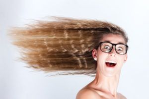 Frau mit großen Augen und Brille und im Wind wehenden Haaren für frische Luft im Kopf beim Brainstorming