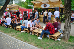 Holzhütten und Holzbänke im Freien mit Besuchern einer Roadshow als mobiles Marketing Instrument