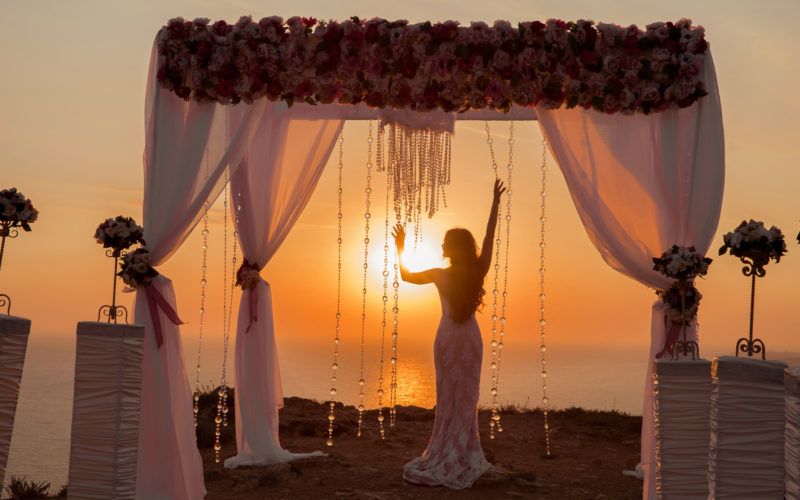 Braut nach ihrer Hochzeit am Meer mit einem Hochzeitszelt und Sonnenuntergang