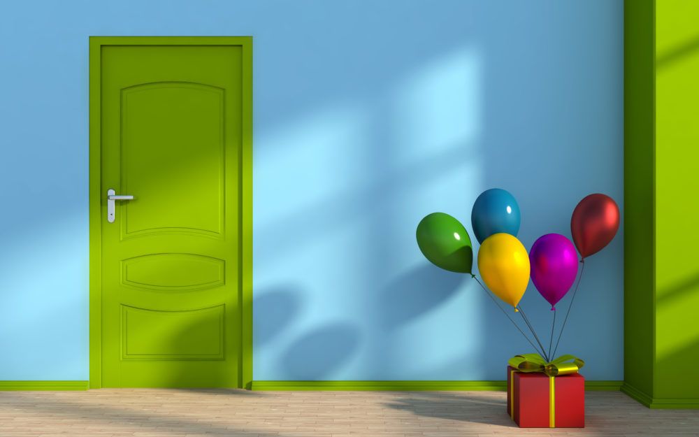 Blauer Raum mit grüner Tür, in dem eine Geschenkbox steht, an die Luftballons gebunden sind