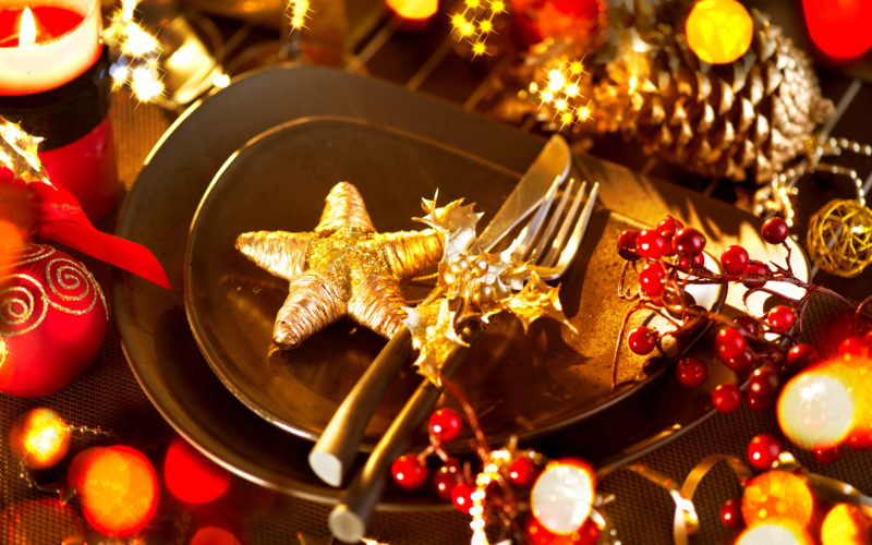 Weihnachtsfeier in Duisburg; Weihnachtlich dekorierter Tisch mit Tellern, Besteck, Kerzen und Sternen