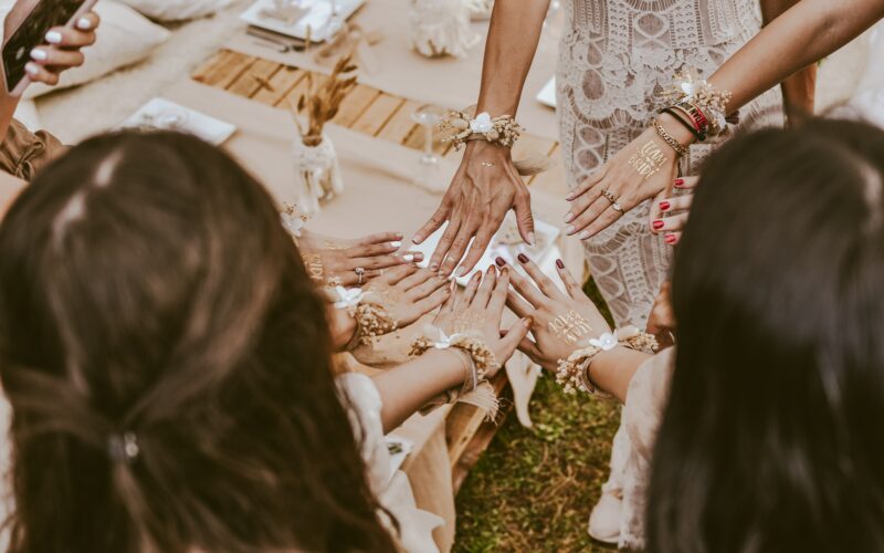 Mehrere junge Frauen halten bei einem Junggesellenabschied ihre Hände, mit "Team Bride" Stickern, zusammen