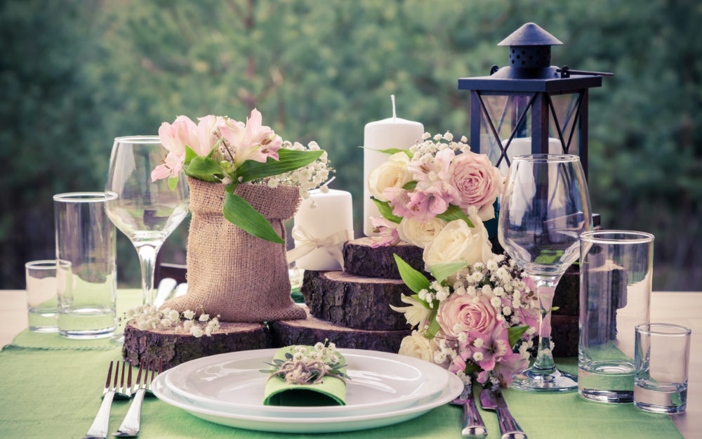 Rustikale Tischdekoration für eine Hochzeit mit Blumen, Holzscheiben und einer Laterne