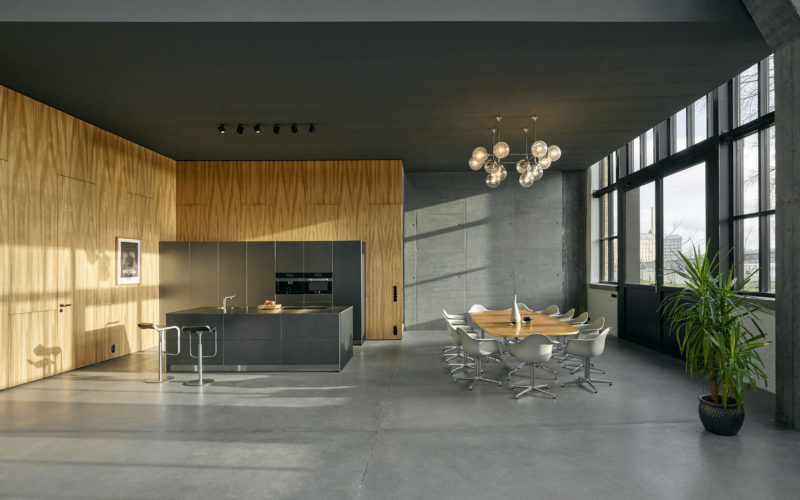 Helles Eventstudio mit einer modernen offenen Küche und einem großen Esstisch mit Stühlen