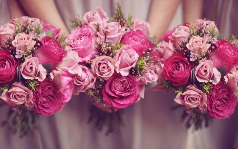 Drei Brautjungfern in rosanem Kleid halten drei pinke Blumensträuße, eventlocations