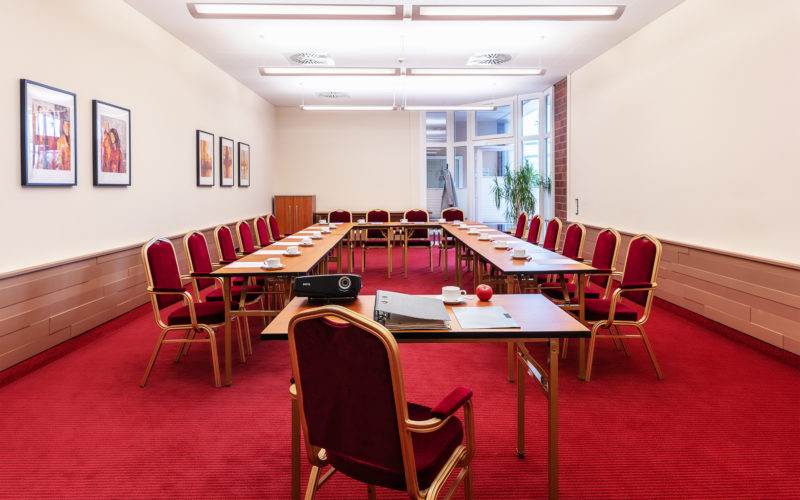 Großer Meetingraum mit Tischen, Stühlen und rotem Teppich