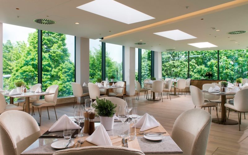 Eventlocations für bis zu 100 Personen in Frankfurt - Hell eingerichtetes Restaurant mit Fensterfront und grünen Bäumen