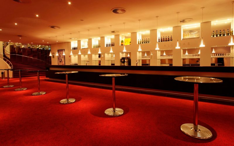 Beleuchteter Barbereich mit Rundtischen und rotem Teppich in einer schönen Location mit hoher Kapazität, Eventlocations für bis zu 1000 Personen in Hamburg