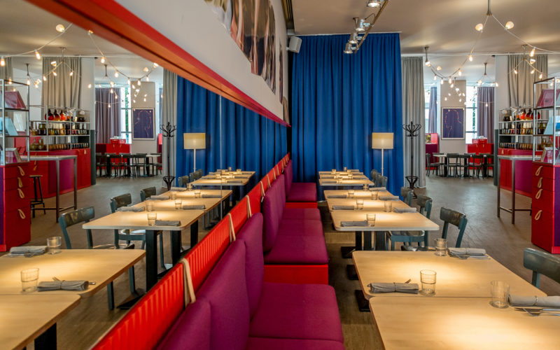 Modernes Restaurant mit roten Sitzbänken und hellen Holztischen