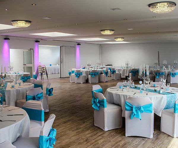 Hochzeitssaal mit weißen Stühlen mit blauen Schleifen