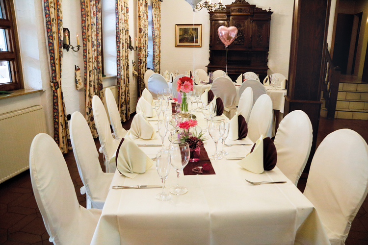 Hochzeitslocation in Dinslaken. Langer weißer bedeckter Tisch mit weißen Stühlen