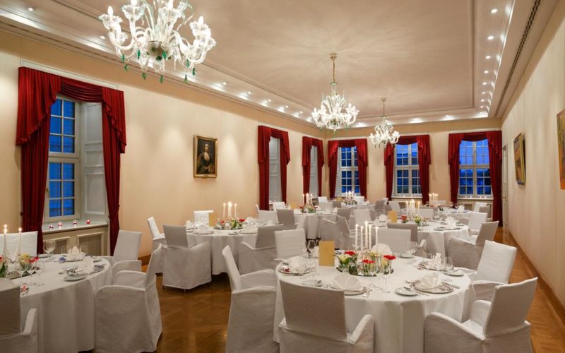Eleganter historischer Raum mit Banketttischen und roten Vorhängen, Firmenfeier in Dresden