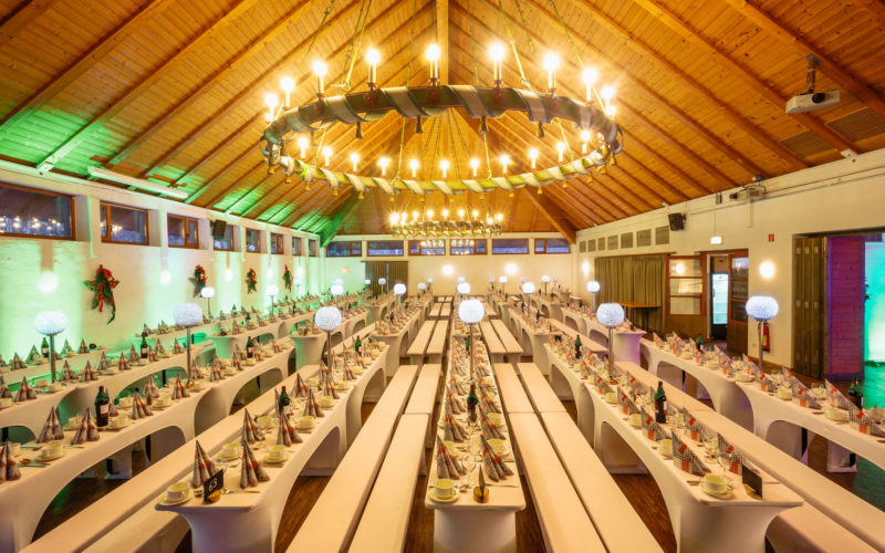 Große Eventhalle mit vielen langen Tischen und Bänken