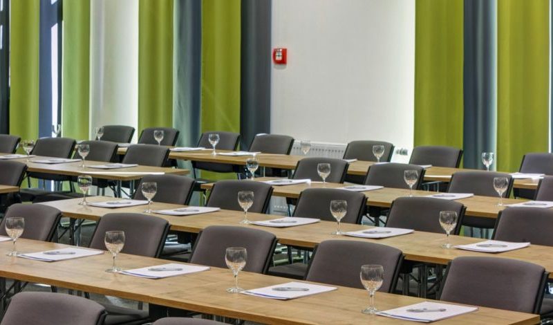 Bestuhlte Eventlocation mit Holztischen und grünen Wandelementen, Firmenfeier in Augsburg