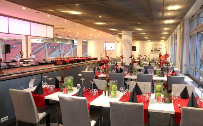 Eventlocation im Stadion mit modernen Innenaustattung und gedeckten Tischen mit rot und schwarz Elementen
