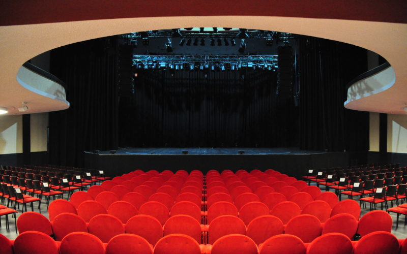 Große Konzerthalle mit einer Bühne und vielen roten Stühlen