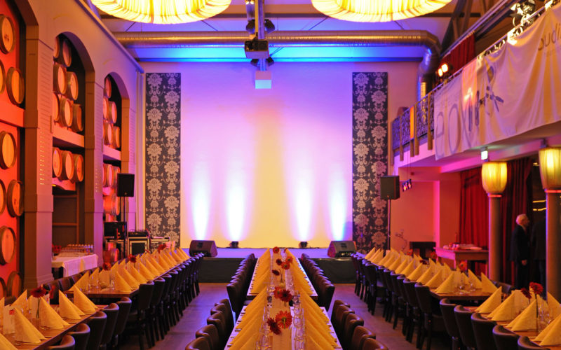 Schöne Eventlocation mit einer Bühne, Tischen und Stühlen; Silvesterparty in Frankfurt