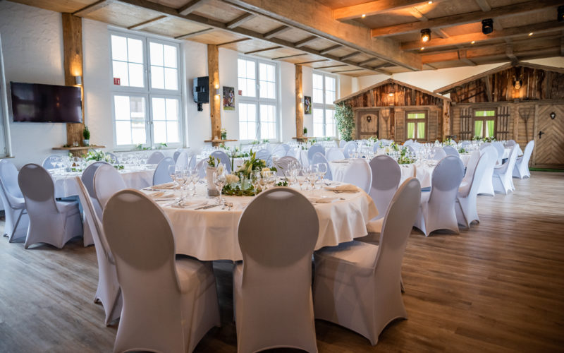 Saal mit Holzboden und weiß eingedeckten Hochzeitstischen; Hochzeitslocation in Reutlingen