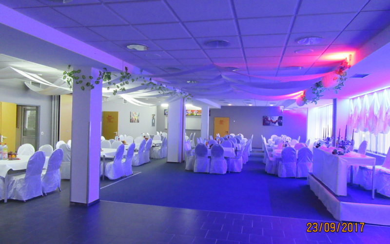 Partyraum für eine Firmenfeier in Schwerin, mit Club Beleuchtung und weiß gedeckten Tischen, Tanzfläche