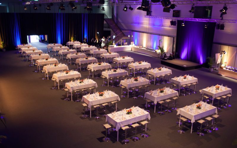 Große Eventhalle mit Tischen, Stühlen und einer Bühne, Firmenfeier in Heilbronn