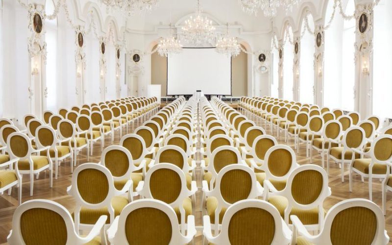 Viele , weiße Stühle in hellem und offenem Raum