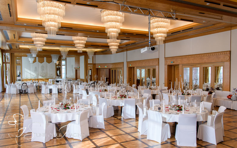Raum mit gedeckten runden Tischen und Stühlen sowie Kronleuchtern an der Decke; Silvesterparty in Stuttgart