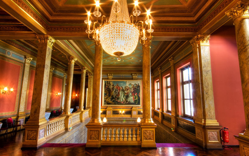 Luxuriöser historischer Saal mit roten Wänden und Marmorbalken