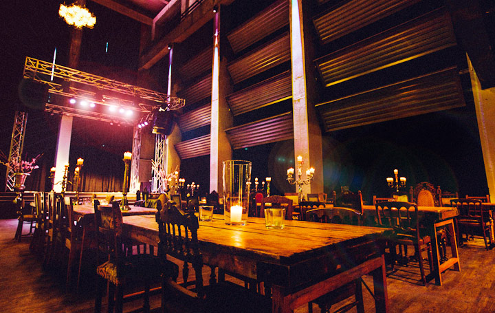 Stilvolle Eventlocation mit Holztischen, Stühlen und einer Bühne