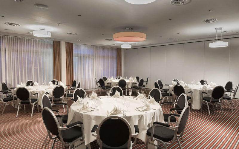 Großer Raum mit runden Tischen, Stühlen und Teppichboden, Firmenfeier in Ludwigshafen am Rhein
