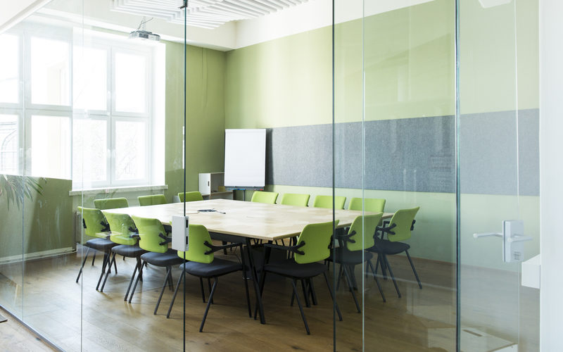 Meetingraum mit einem großen Tisch, Stühlen und grünen Wänden
