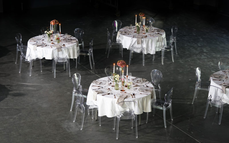 Runde Glastische mit weißer Tischdecke und Blumendekor auf schwarzen Boden; Messehalle in Braunschweig
