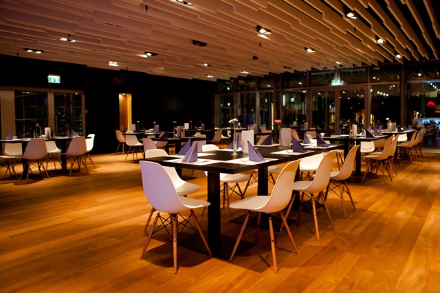 Eleganter Eventraum mit Tischen, Stühlen sowie einer Glaswand