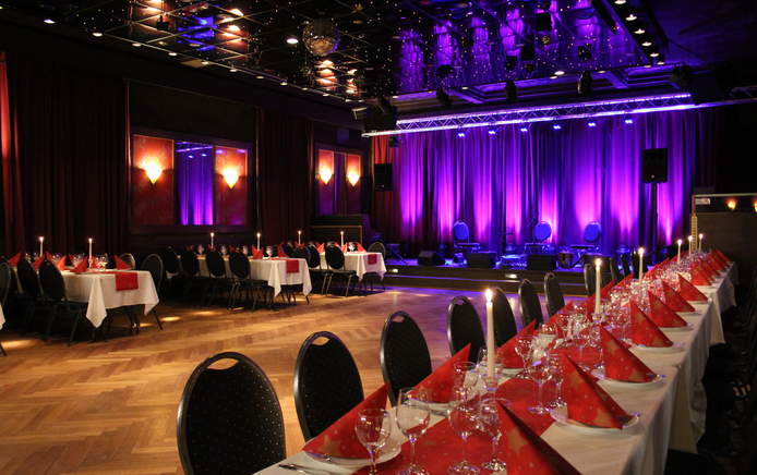 Außergewöhnliche Eventlocations für Firmenfeier in Erlangen, riesige Halle mit moderner Beleuchtung und eleganter gedeckter Tafel mit Tanzfläche