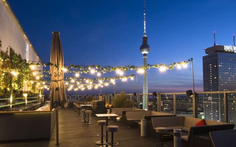 Schöne Terrasse mit Lichterketten, Sitzbänken, Stühlen sowie einer traumhaften Aussicht über Berlin und den Fernsehturm