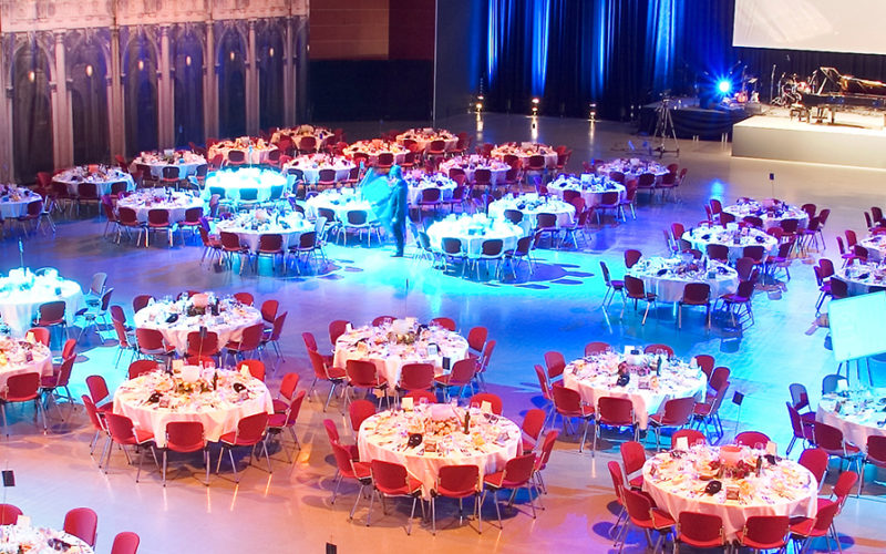 Runde Tische gedeckt für ein Dinner vor einer Bühne; Messehalle in Bochum