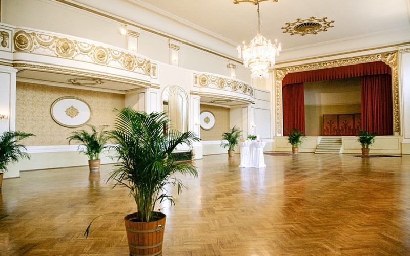 Festlicher Saal in edler Inneneinrichtung, braunen Boden und weiß verzierten Wänden