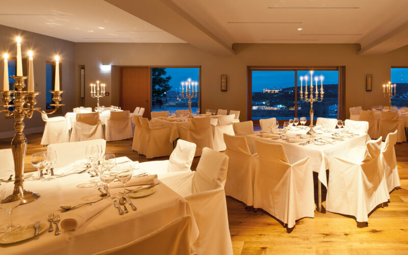 Stilvoller Raum mit großen Fenstern und schön gedeckten weißen Tischen und Stühlen; Silvesterparty in Schweinfurt