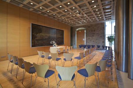 Moderner Raum mit Stühlen und einem großen Fernseher an der Wand; Tagungsraum und Konferenzraum in Witten