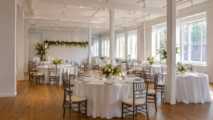 Helle Eventlocation mit gedeckten runden Tischen, Blumen und natürlichem Licht