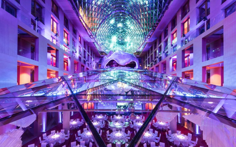 Festlich gedeckte runde Tische im Tagungsraum mit lila Lichtshow auf Glaskuppel